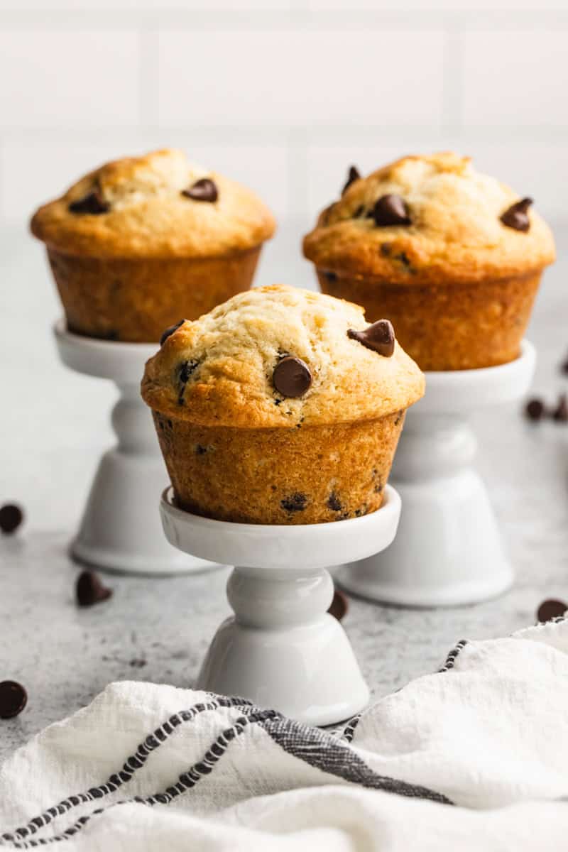 Three easy Chocolate Chip Muffins on top of little white muffin stands, ready to enjoy. 