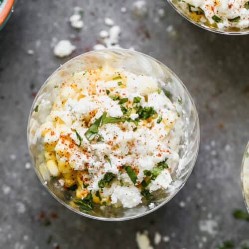 The best esquites recipe with fresh corn in a cup topped with mexican crema, mayonnaise, cheese, chili powder, and cilantro, ready to enjoy!
