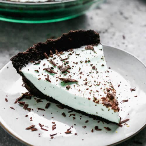 A slice of an easy Grasshopper Pie with a creamy mint filling on an Oreo Crust, topped with chocolate shavings.