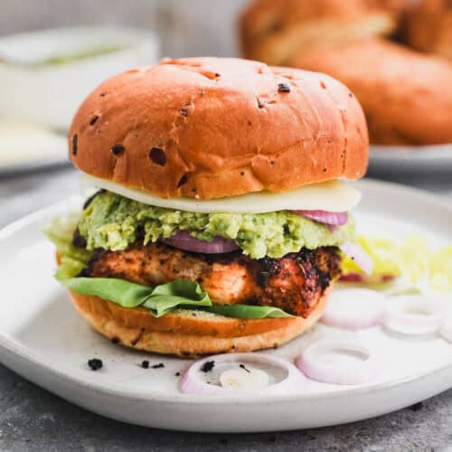 The best Grilled Chicken Burger served on a bun with lettuce, onions, cheese, and homemade guacamole.