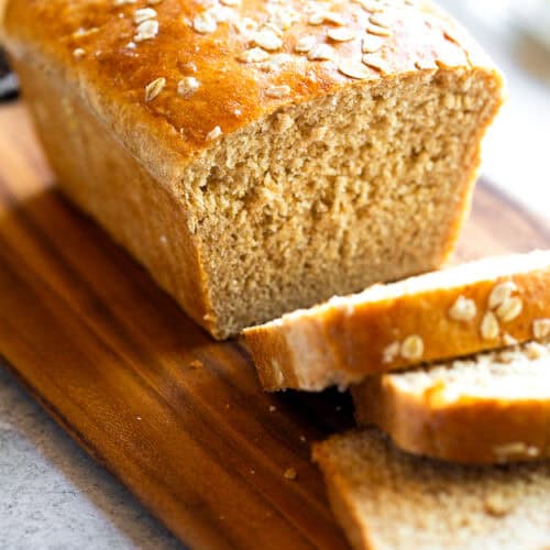 A loaf of honey Oatmeal Bread with a few slices cut, ready to eat.
