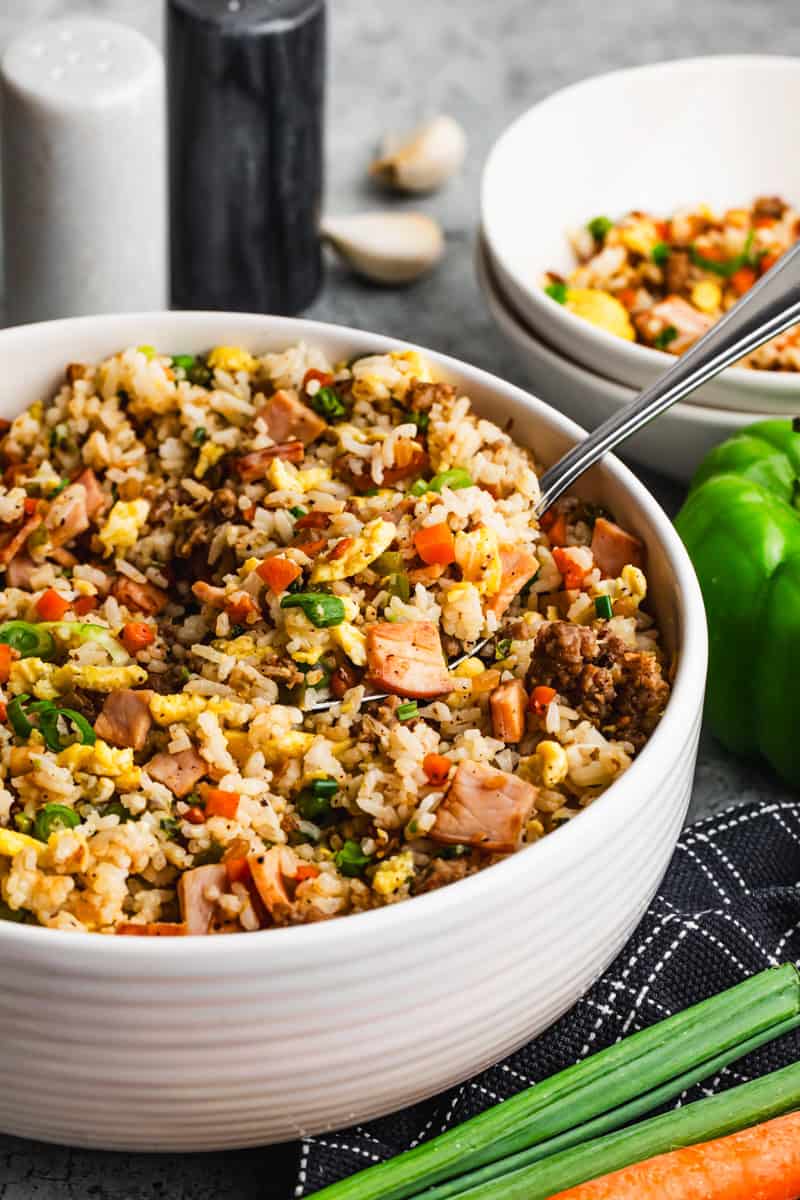 An easy Breakfast Fried Rice recipe in a bowl, with scrambled eggs, Canadian bacon, sausage, and veggies. 