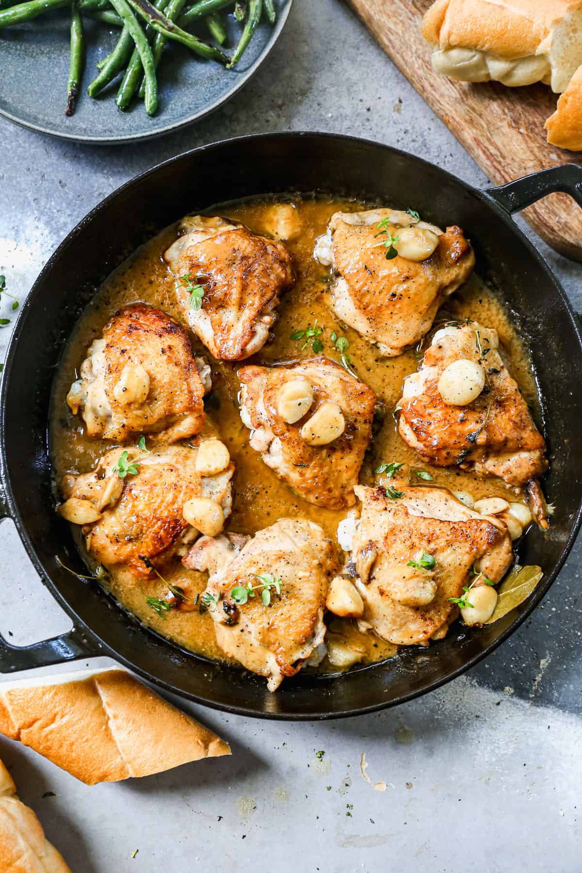 A creamy garlic chicken recipe made with chicken thighs and 40 cloves of garlic in a cast iron pan, ready to serve. 