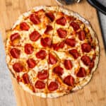 This high protein pizza dough recipe made into a delicious pepperoni pizza on the cutting board, sliced and ready to serve.