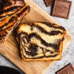 A slice of an easy Chocolate Babka recipe with chocolate swirls throughout on a cutting board.