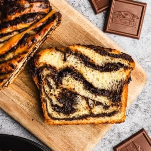 A slice of an easy Chocolate Babka recipe with chocolate swirls throughout on a cutting board.