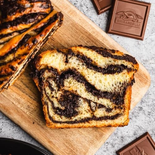 A slice of an easy Chocolate Babka recipe with chocolate swirls throughout on a cutting board.