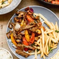 Lomo Saltado served on a plate with french fries.