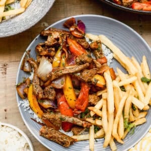 Lomo Saltado served on a plate with french fries.