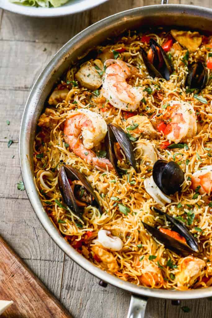 A pan of authentic Fideuà with clams, mussels, and shrimp nestled in the noodles, ready to serve.