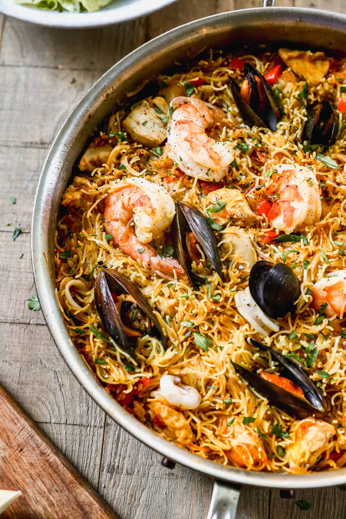 A pan of authentic Fideuà with clams, mussels, and shrimp nestled in the noodles, ready to serve.