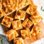 Homemade Focaccia bread on a cutting board, cut into squares.