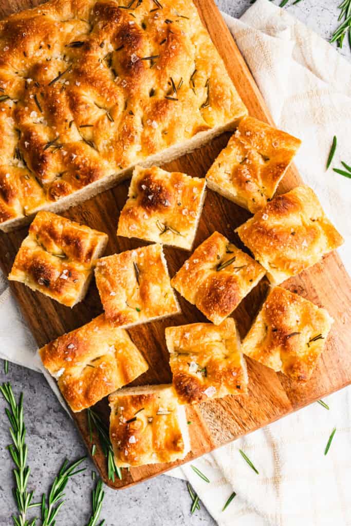 Homemade Focaccia bread on a cutting board, cut into squares.