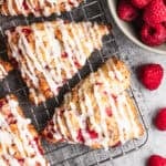 The best raspberry scones recipe made with fresh raspberries cooling on a rack and drizzled with a simple glaze.