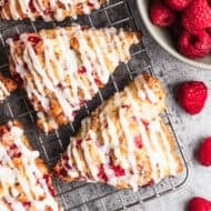 The best raspberry scones recipe made with fresh raspberries cooling on a rack and drizzled with a simple glaze.