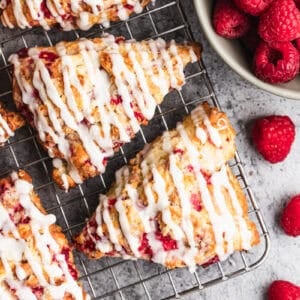 The best raspberry scones recipe made with fresh raspberries cooling on a rack and drizzled with a simple glaze.