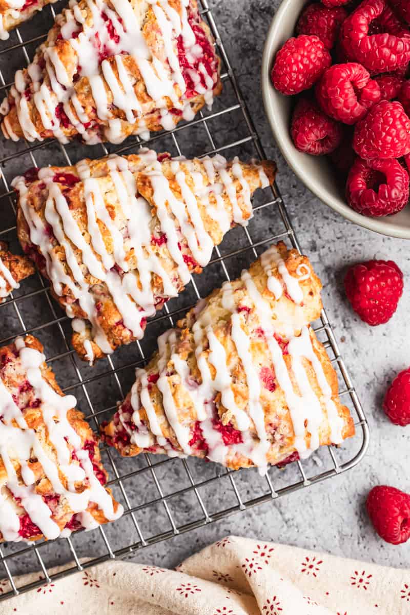 The best raspberry scones recipe made with fresh raspberries cooling on a rack and drizzled with a simple glaze.
