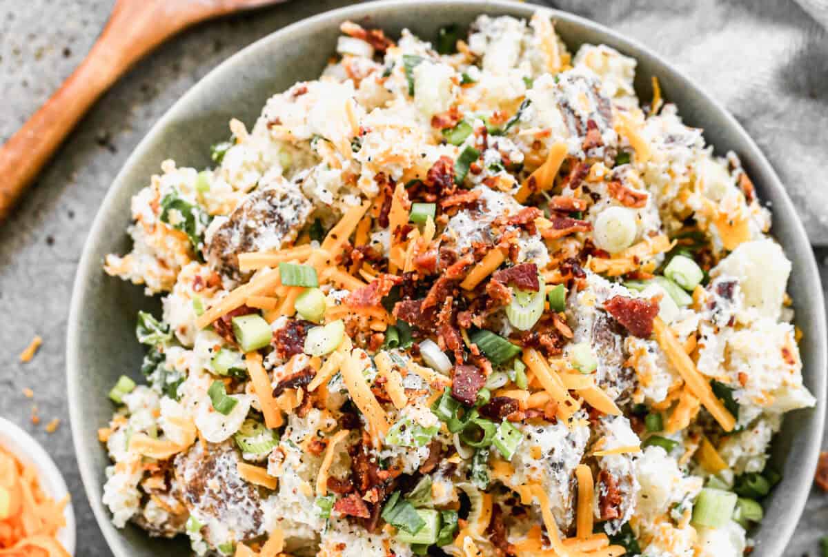 This loaded baked potato salad is the perfect make-ahead side dish, topped with cheese, bacon, and green onions for the ultimate crowd-pleaser.