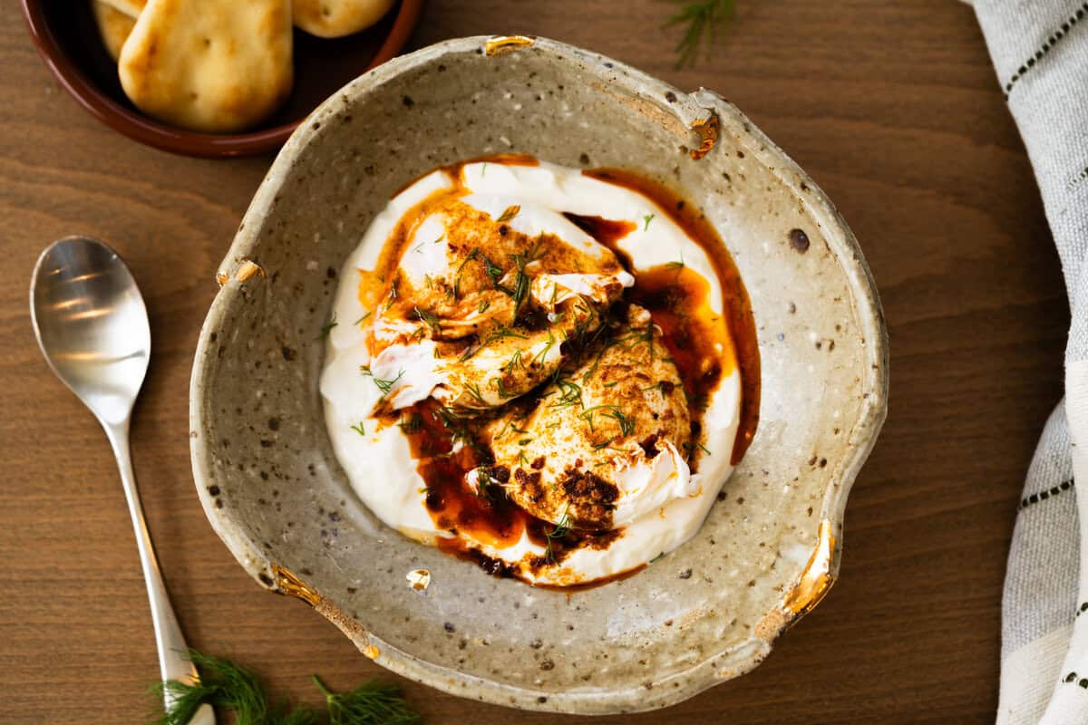 This easy Turkish Eggs recipe has perfectly poached eggs on a bed of lemon garlic yogurt, topped with a drizzle of a quick spiced chili butter. 