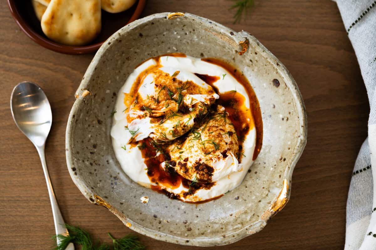 This easy Turkish Eggs recipe has perfectly poached eggs on a bed of lemon garlic yogurt, topped with a drizzle of a quick spiced chili butter. 