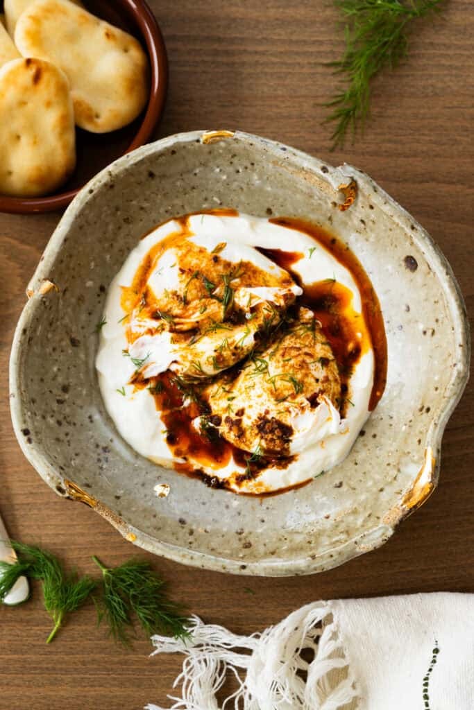 This easy Turkish Eggs recipe has perfectly poached eggs on a bed of lemon garlic yogurt, topped with a drizzle of a quick spiced chili butter.