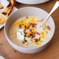 This easy Baked Potato Soup recipe is creamy, flavorful, and restaurant worthy! Top this cozy soup with cheese, bacon, and sour cream and dip the crispy potato skins.