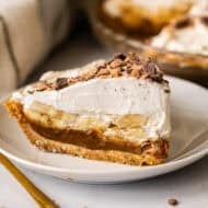 This easy Banoffee Pie recipe is simple to make but the flavors compliment each other perfectly with a graham cracker crust, dulce de leche, banana slices, and whipped cream with toffee bits on top.