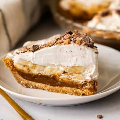 This easy Banoffee Pie recipe is simple to make but the flavors compliment each other perfectly with a graham cracker crust, dulce de leche, banana slices, and whipped cream with toffee bits on top.