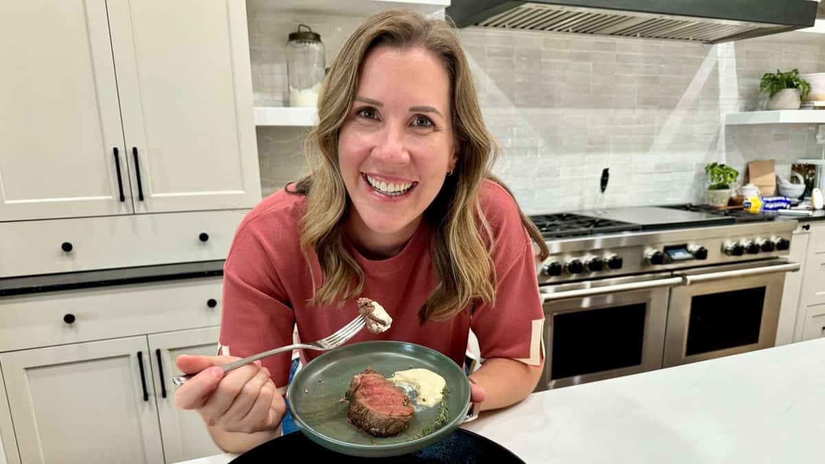 Lauren Allen with a plate of Beef Tenderloin that is perfectly cooked and being dipped in an orange-infused horseradish sauce.