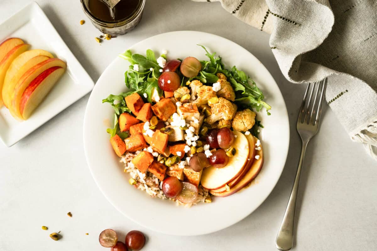This healthy Nourish Bowl recipe is loaded with roasted chicken, sweet potatoes, and cauliflower over wild rice with fresh apples, grapes, and a quick balsamic vinaigrette. It's ready in just 30 minutes and tastes fresh and flavorful!