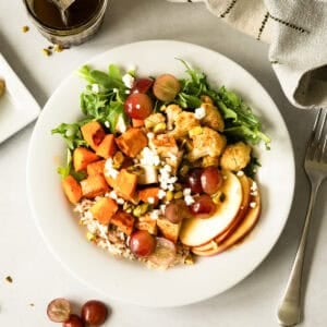 This healthy Nourish Bowl recipe is loaded with roasted chicken, sweet potatoes, and cauliflower over wild rice with fresh apples, grapes, and a quick balsamic vinaigrette. It's ready in just 30 minutes and tastes fresh and flavorful!