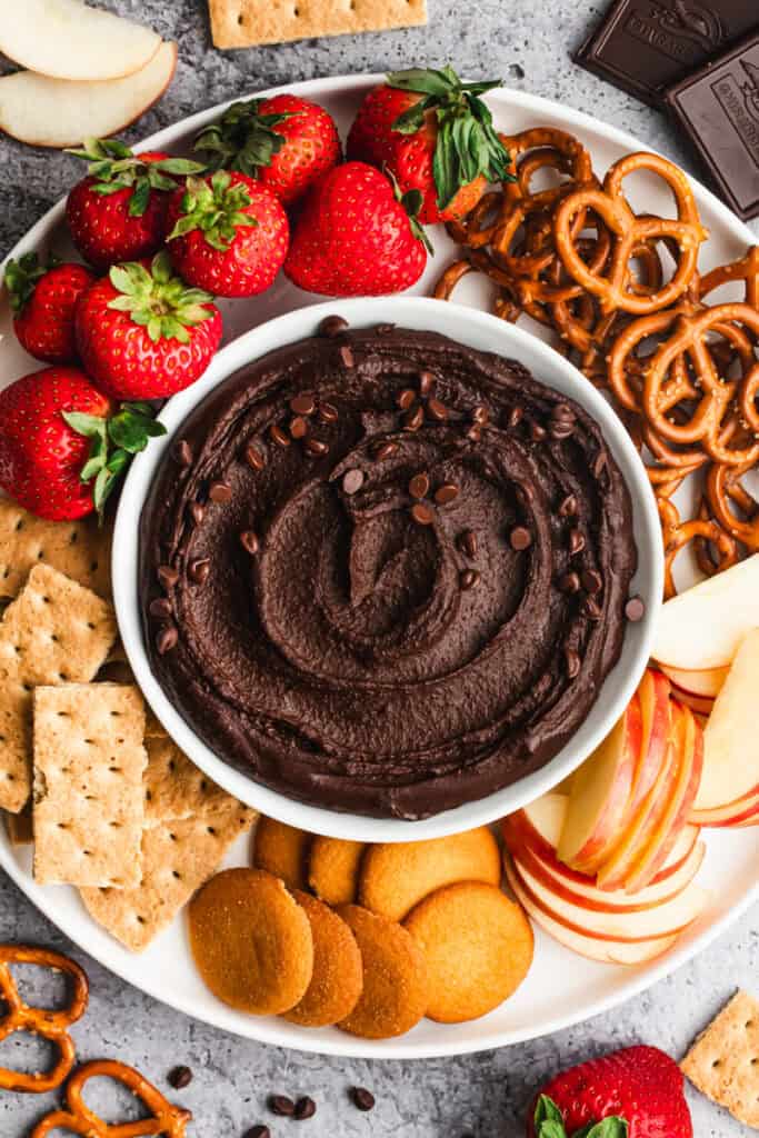 This easy Chocolate Hummus recipe is a healthier dessert that tastes just as indulgent as anything! Dip whatever fruit, crackers, or cookies you'd like for the ultimate party dip!