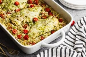 This easy Pesto Chicken Casserole recipe only takes 10 minutes to prep and bakes into a cheesy, creamy pesto chicken and rice dish that is flavorful and bound to get compliments!