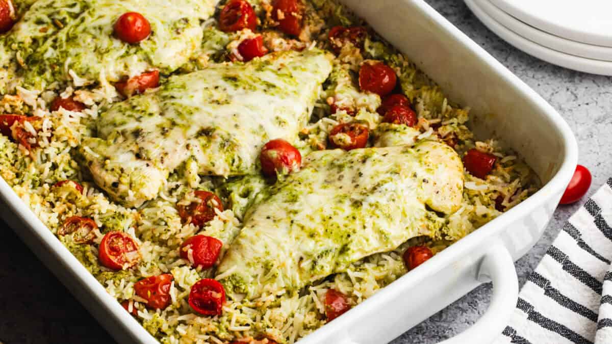 This easy Pesto Chicken Casserole recipe only takes 10 minutes to prep and bakes into a cheesy, creamy pesto chicken and rice dish that is flavorful and bound to get compliments!