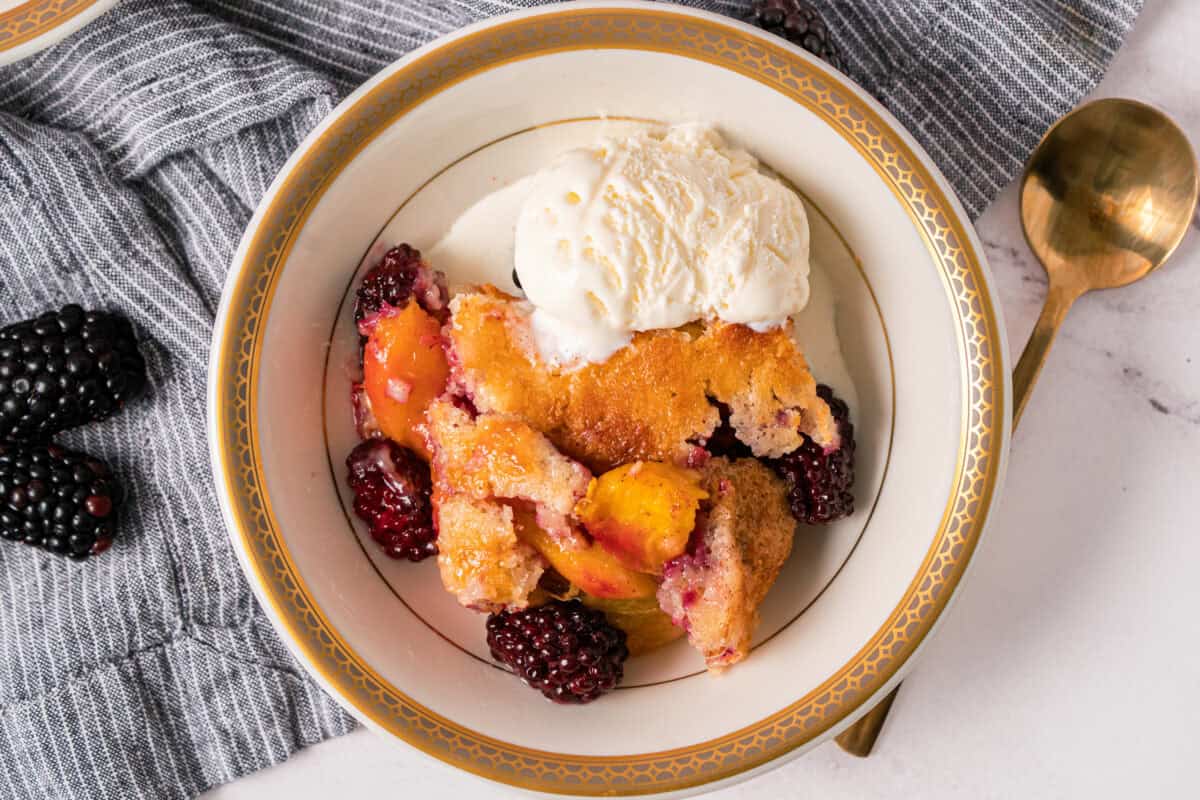 This easy Peach Blackberry Cobbler recipe is bursting with fresh fruit under a golden and buttery topping. Enjoy it year round with fresh or canned peaches.