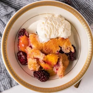 This easy Peach Blackberry Cobbler recipe is bursting with fresh fruit under a golden and buttery topping. Enjoy it year round with fresh or canned peaches.