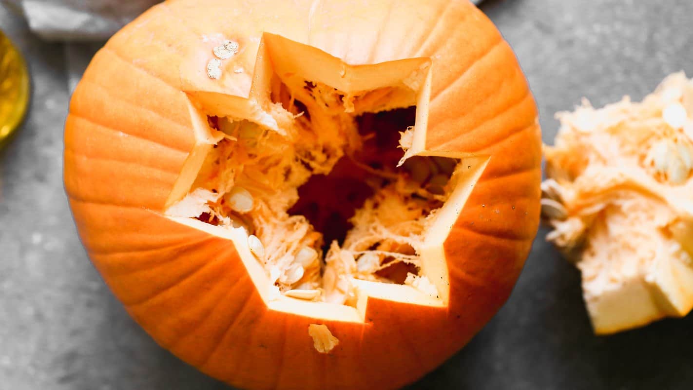 A carved pumpkin with the seeds and pulp scooped out for roasting
