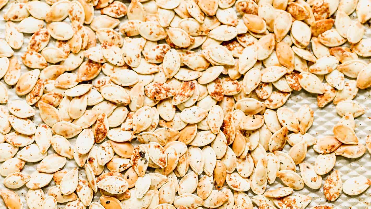Golden roasted pumpkin seeds seasoned with salt and cayenne on a baking sheet